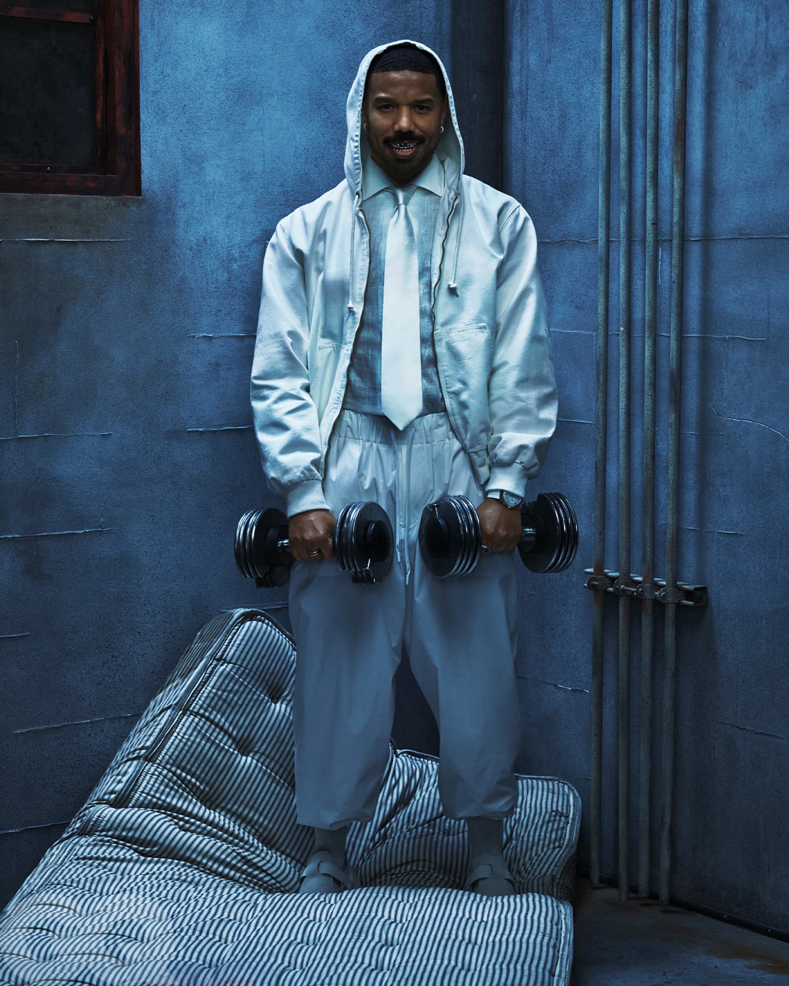 Michael B Jordan — dumbbells against blue wall