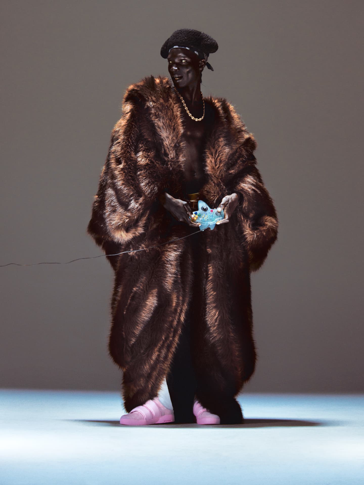 Model in oversized fur coat holding a game controller