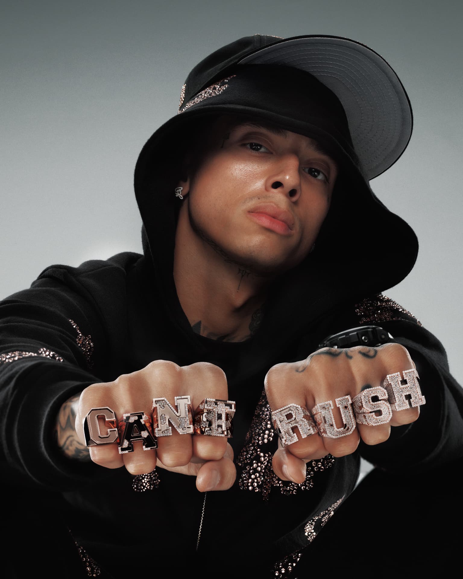 Central Cee — close-up portrait with CANT RUSH knuckle rings and bucket hat