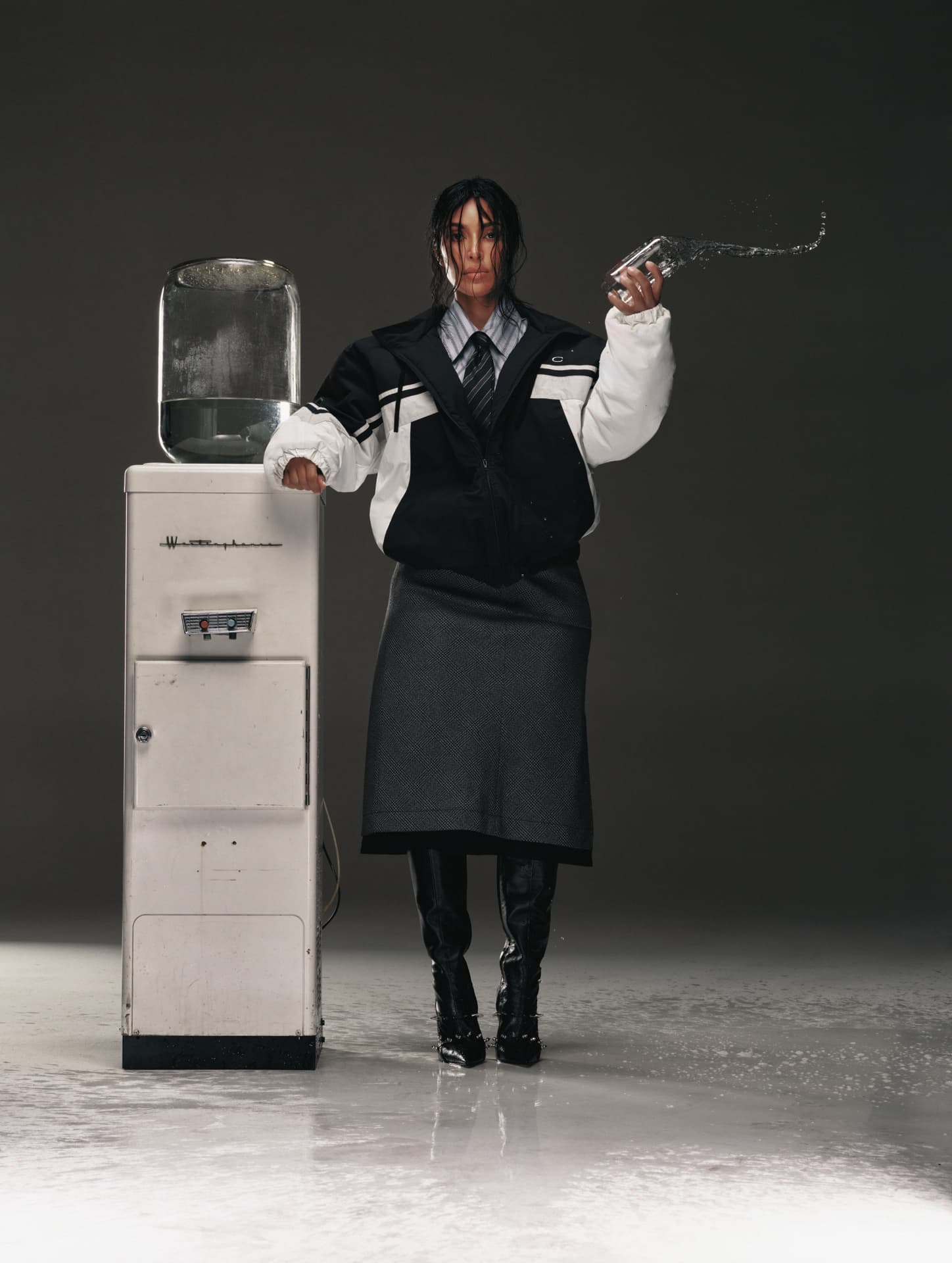 Kim Kardashian — GQ portrait in black-and-white varsity jacket beside a water cooler