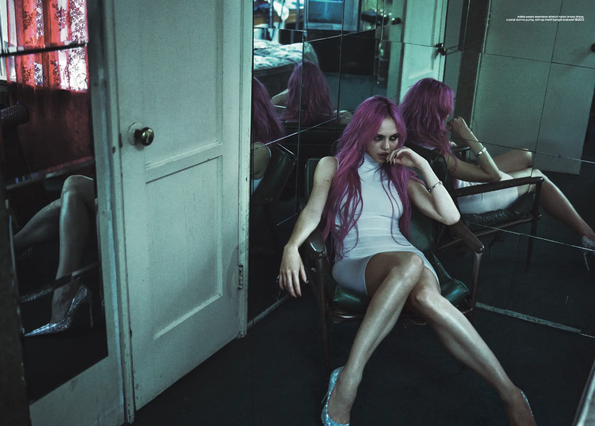 ADÉLA — seated in a mirrored room wearing a white jersey dress