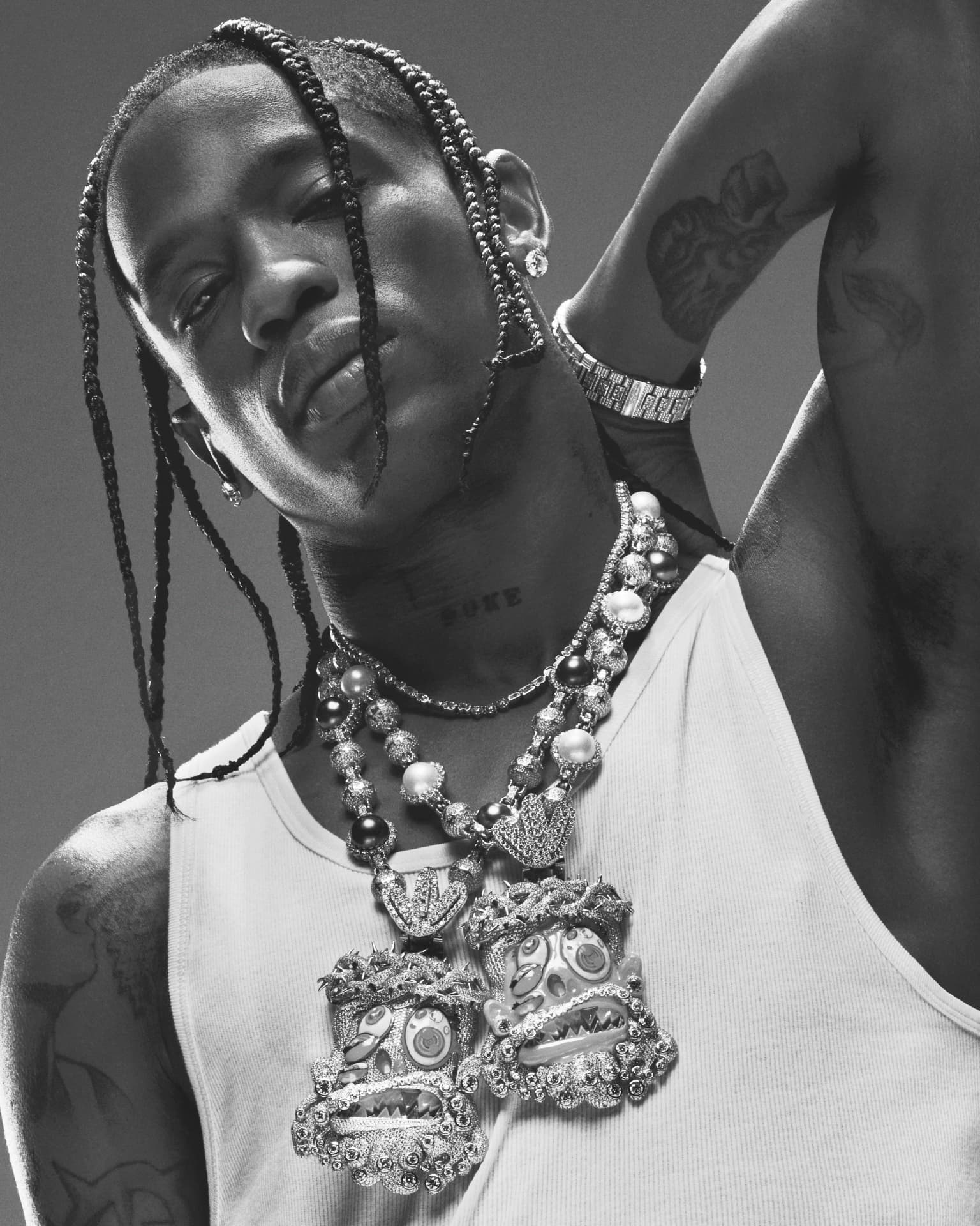 Travis Scott — black and white portrait with layered pearl and crown pendant necklaces