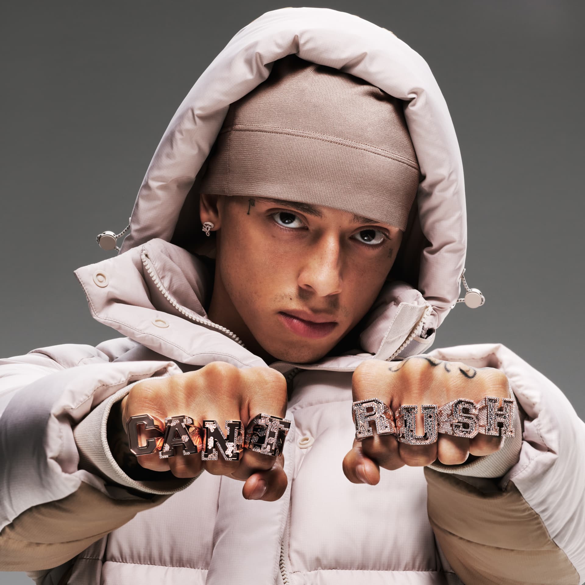 Central Cee — hooded portrait with CANT and RUSH knuckle rings
