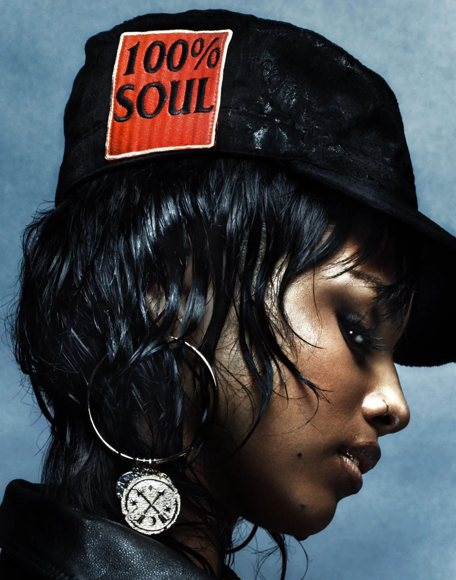 TYLA — close-up side profile with '100% Soul' cap and large hoop earrings