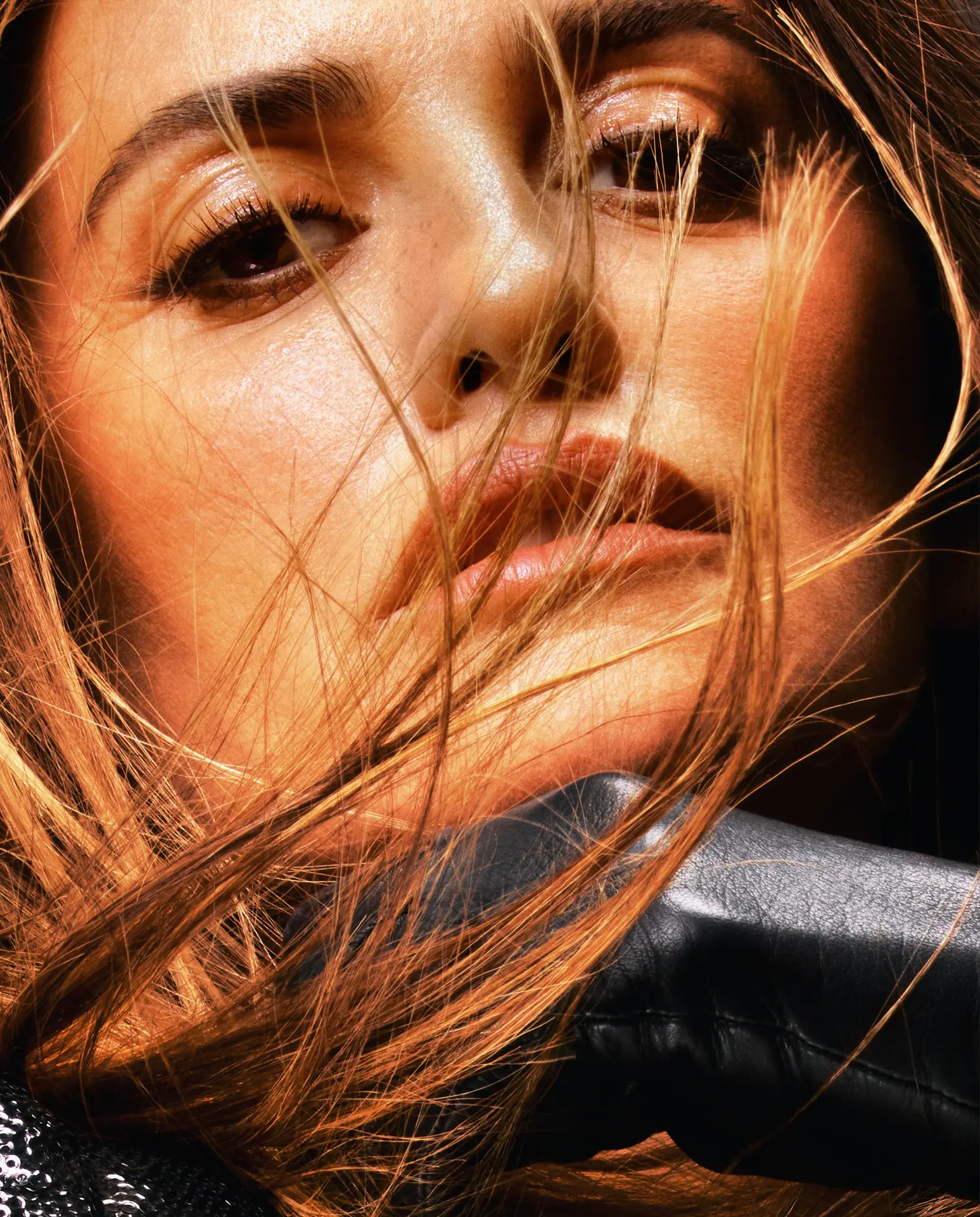 Penélope Cruz — sunlit close-up portrait with windswept hair and black leather jacket