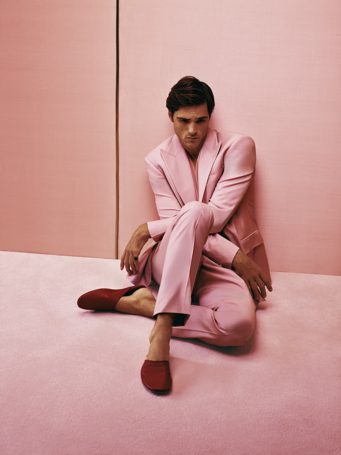 Jacob Elordi — seated on the floor in pink suit and red shoes