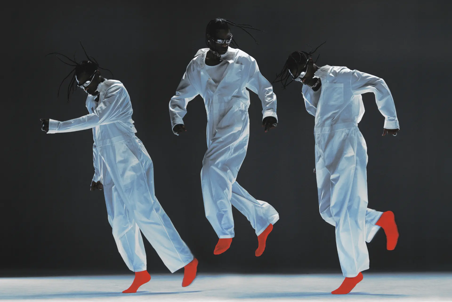 Travis Scott — three figures in white jumpsuits with red socks leaping