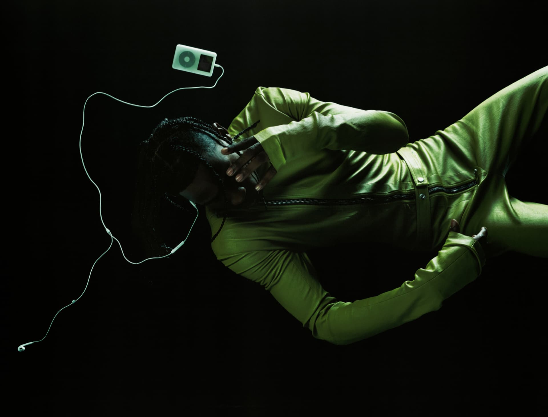 Travis Scott — figure in green leather jacket with iPod and earphones floating in darkness