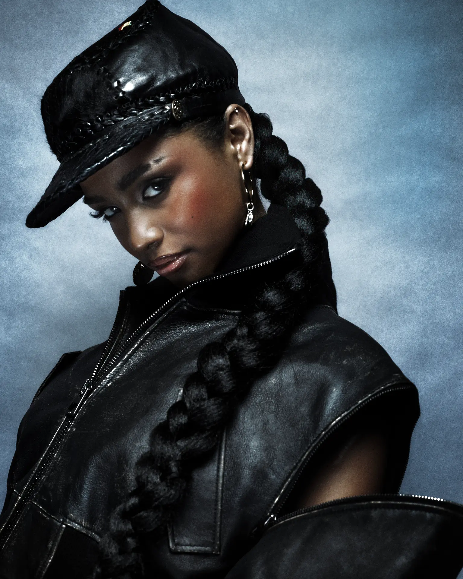 TYLA — close-up profile in black cap and leather jacket with hoop earrings