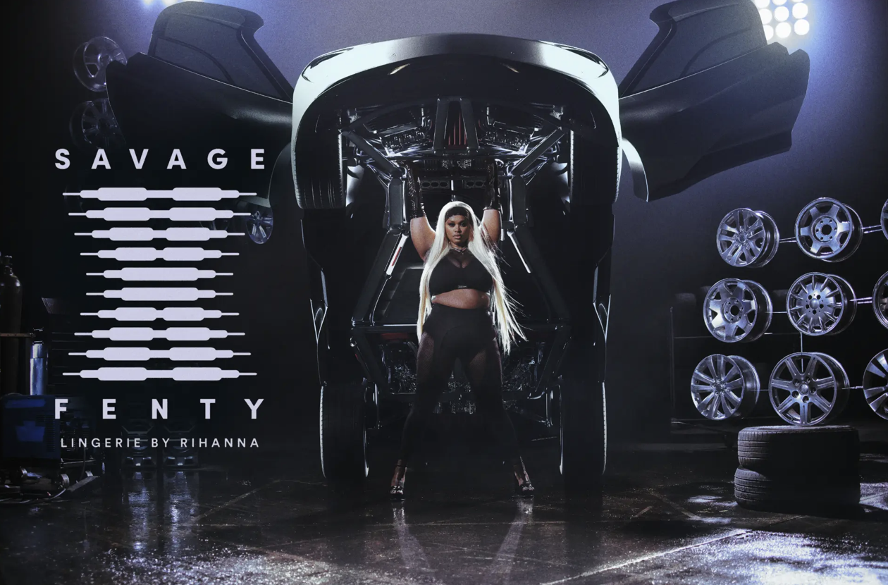 Savage x Fenty — figure beneath a raised car in a garage with logo